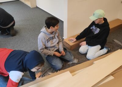 Drei Schüler bauen ein Regal auf.