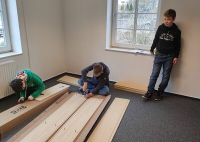 Drei Schüler bauen ein Regal auf.