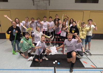 Siegerfoto der jubelnden Mannschaft vor einem Floorballtor mit der Urkunde über den ersten Platz