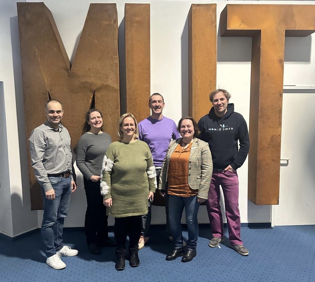 Sechs Lehrkräfte der HORIZONTA inklusive des Schulleitungsteams vor einer großen Skulptur des Wortes Mut in Großbuchstaben aus mit Rost überdeckten Metall